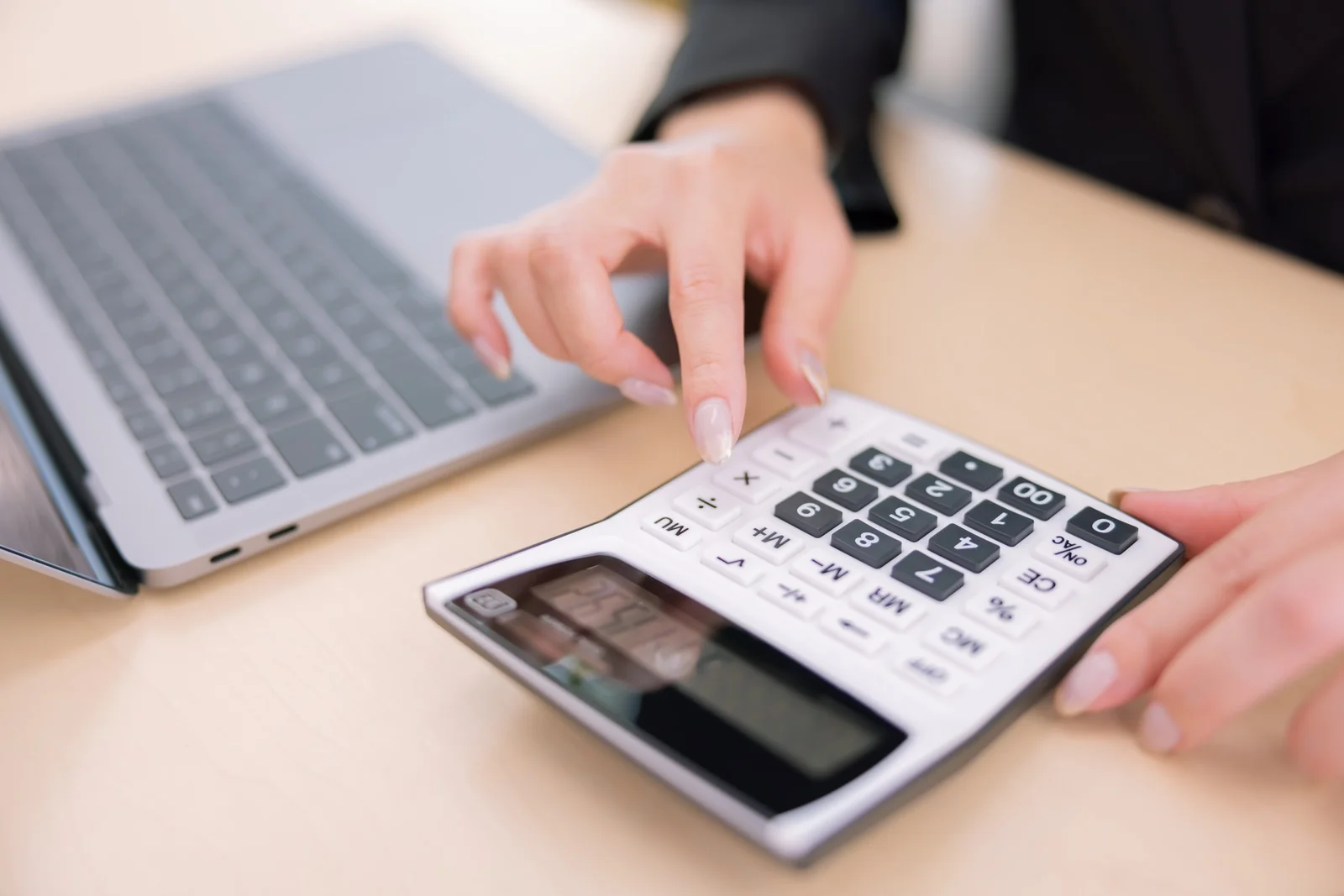 事務員gパソコンを見ながら電卓を打っている